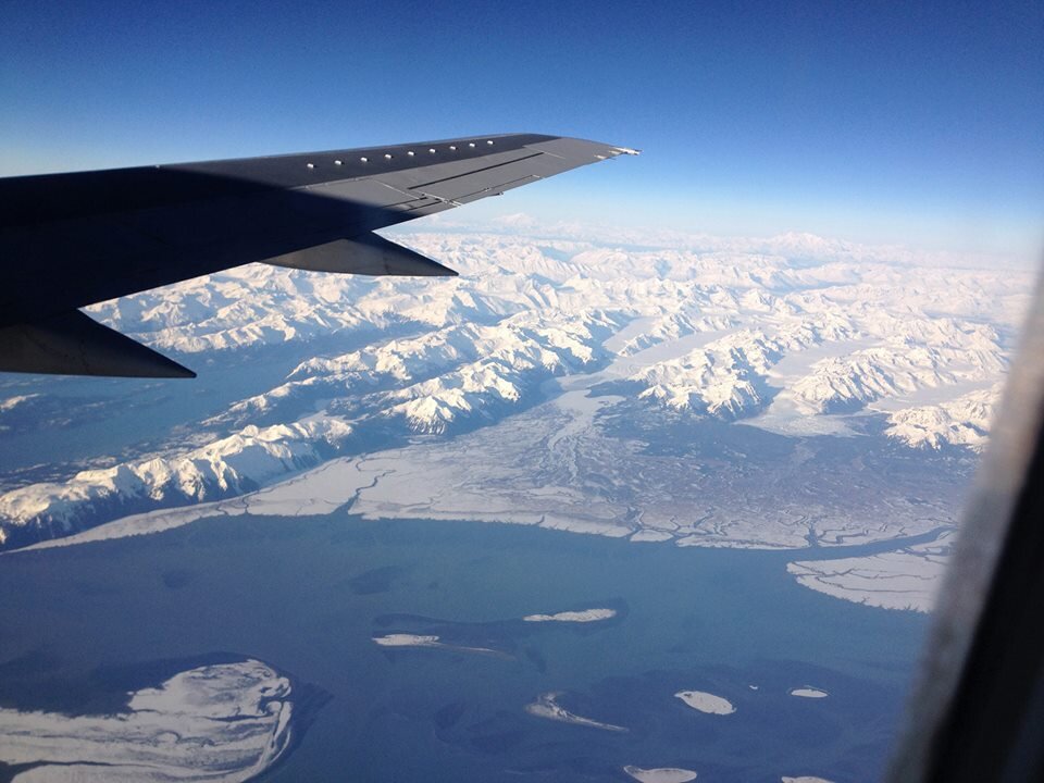 Snow-covered mountains and coastline seen from an aircraft window on the way in
