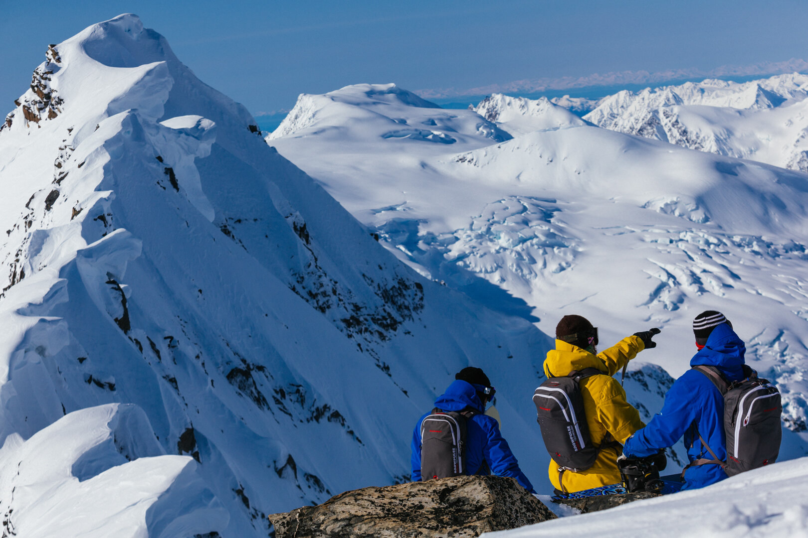 A group of riders sitting on a ridge top looking out across the range